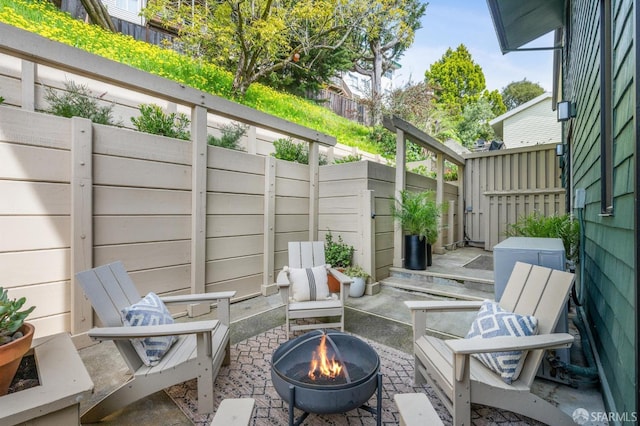 view of patio featuring fence and a fire pit