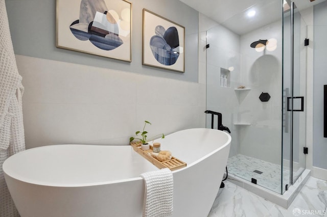 bathroom with a stall shower, marble finish floor, and a freestanding bath