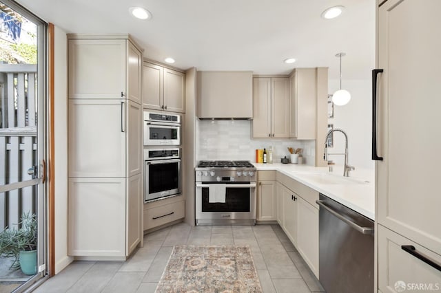 kitchen with decorative backsplash, stainless steel appliances, light countertops, a sink, and recessed lighting