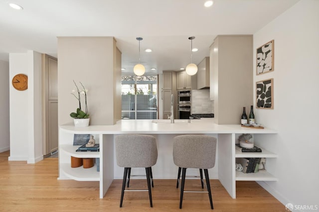 kitchen with light wood-style floors, double oven, a kitchen breakfast bar, and open shelves