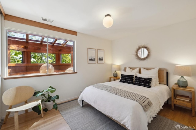 bedroom with visible vents, baseboards, and wood finished floors