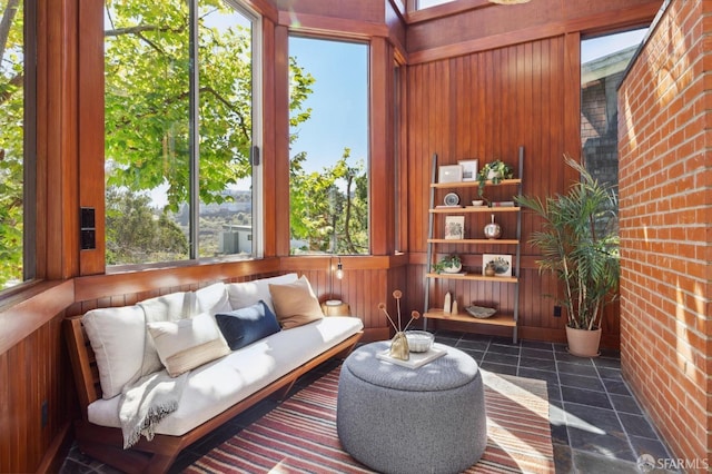 sitting room featuring wooden walls, brick wall, and a healthy amount of sunlight