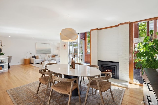 dining room with recessed lighting, a fireplace, light wood-style flooring, and baseboards