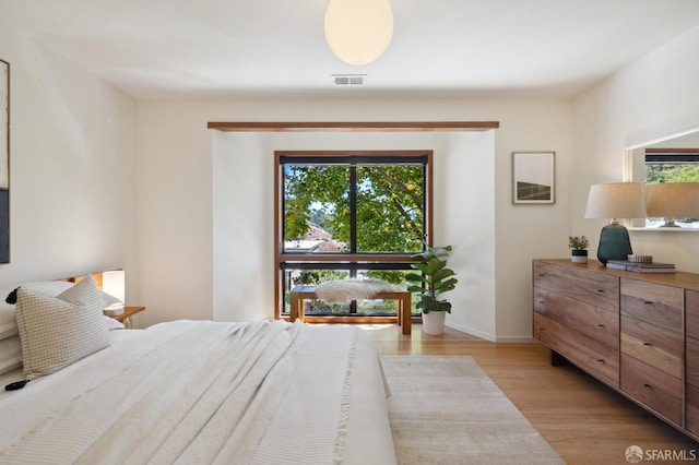 bedroom featuring light wood finished floors, baseboards, and visible vents