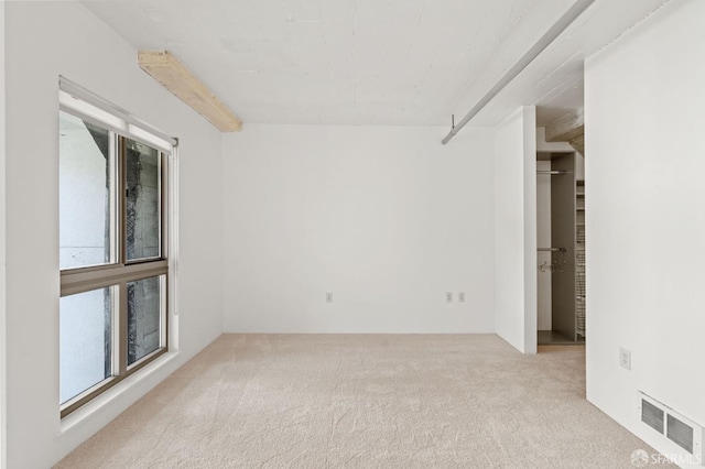 unfurnished room with beamed ceiling and light colored carpet