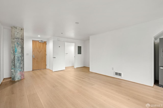 unfurnished living room featuring electric panel, light hardwood / wood-style flooring, and a barn door