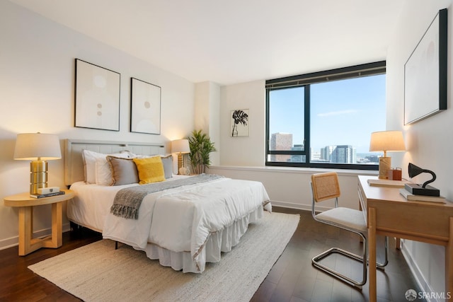 bedroom with a view of city, dark wood-type flooring, and baseboards