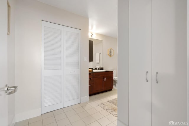 bathroom with a closet, vanity, toilet, and tile patterned floors