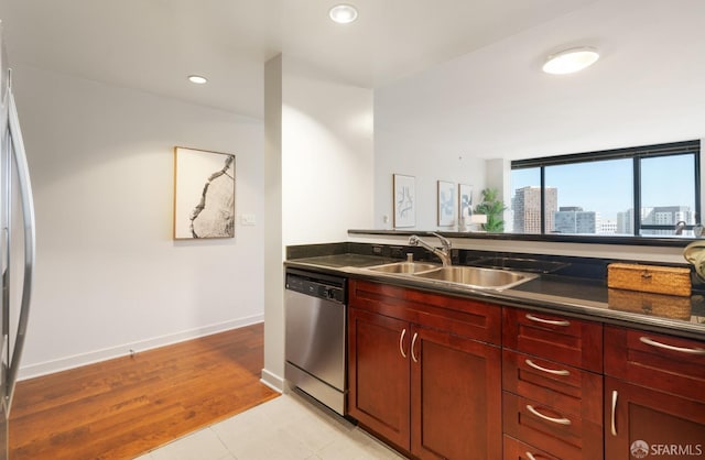 kitchen with reddish brown cabinets, a city view, stainless steel appliances, dark countertops, and a sink