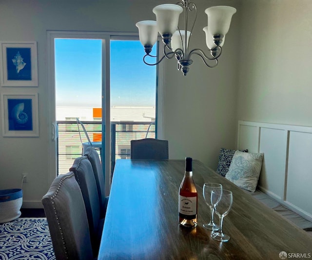 dining area featuring a chandelier, a wainscoted wall, and a decorative wall