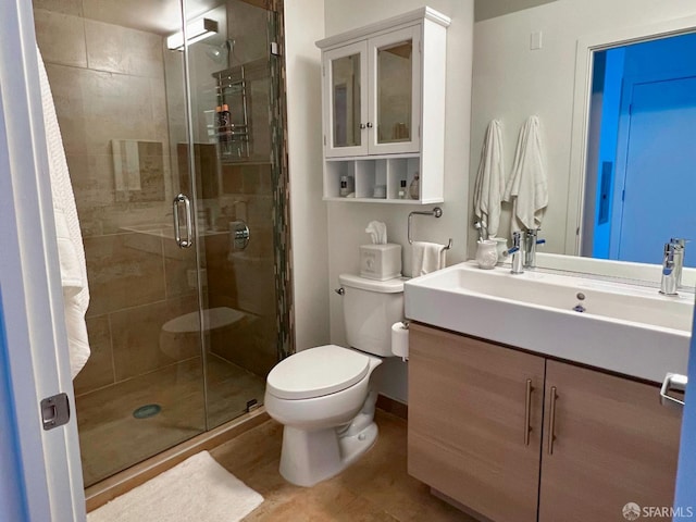 full bathroom featuring a stall shower, baseboards, vanity, and toilet