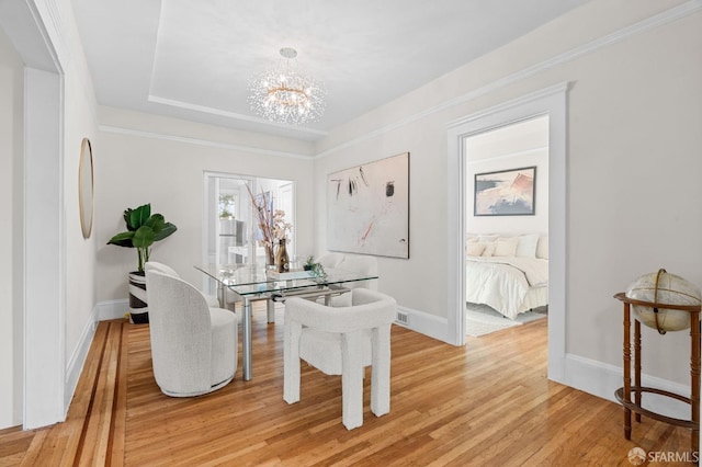 dining room with a tray ceiling, light hardwood / wood-style floors, and a notable chandelier