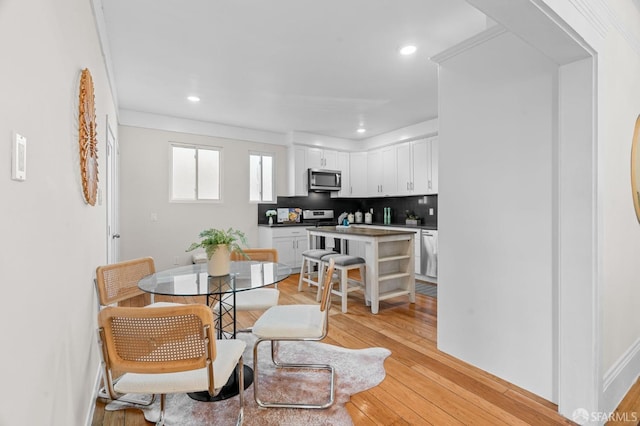 dining area featuring ornamental molding and light wood-type flooring