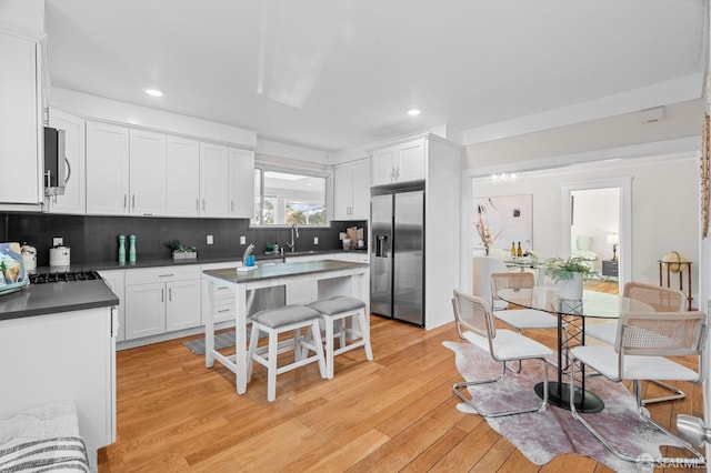 kitchen featuring white cabinetry, sink, backsplash, stainless steel fridge, and light wood-type flooring