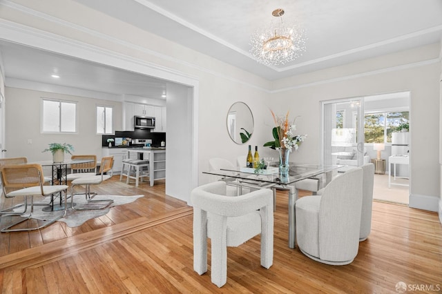 dining space with light hardwood / wood-style floors, an inviting chandelier, and crown molding