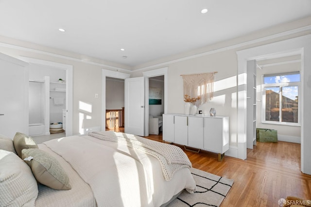 bedroom with connected bathroom, light hardwood / wood-style flooring, multiple windows, and crown molding