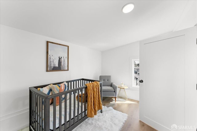 bedroom with a crib and wood finished floors