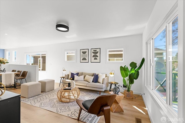 living room featuring light wood-style flooring, visible vents, and baseboards