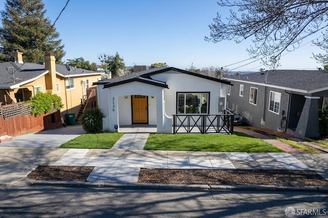 view of front of property with a front yard, fence, and stucco siding