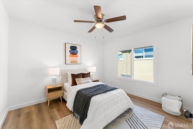 bedroom with wood finished floors, a ceiling fan, and baseboards