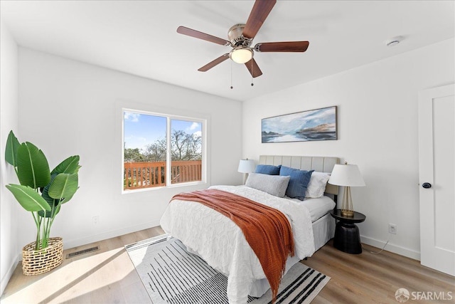 bedroom featuring baseboards, visible vents, ceiling fan, and wood finished floors