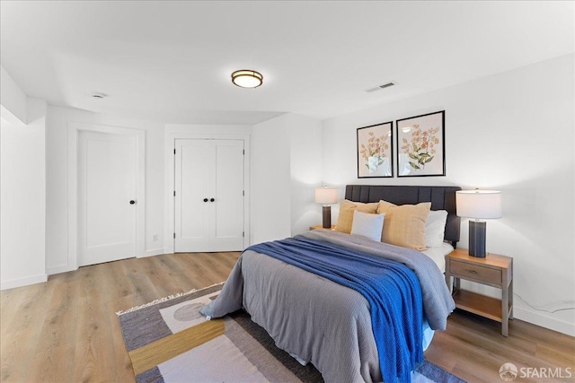 bedroom with wood finished floors, visible vents, and baseboards