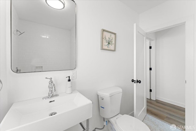 bathroom with wood finished floors, a sink, toilet, and baseboards