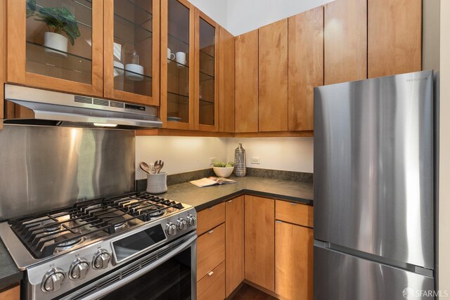 762 Bay St, San Francisco, CA 94109 - kitchen with stainless steel appliances, under cabinet range hood, dark countertops, and glass insert cabinets