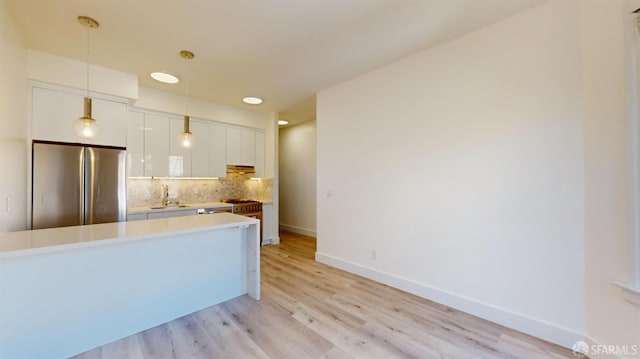 1338 Stevenson St, San Francisco, CA 1906 - kitchen featuring freestanding refrigerator, white cabinetry, tasteful backsplash, light countertops, and light wood-style flooring