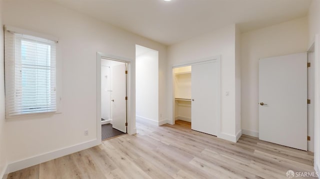 1338 Stevenson St, San Francisco, CA 1906 - unfurnished bedroom featuring light wood-style floors, a walk in closet, ensuite bathroom, and a closet