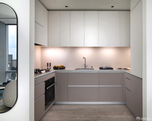 kitchen with sink, white cabinets, light hardwood / wood-style floors, and appliances with stainless steel finishes