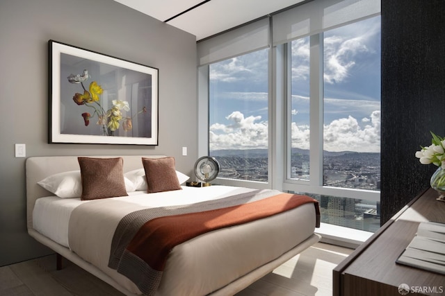 bedroom featuring multiple windows, a mountain view, and light hardwood / wood-style flooring