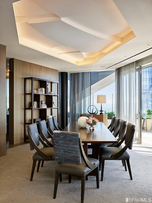 dining room with a tray ceiling and a wall of windows