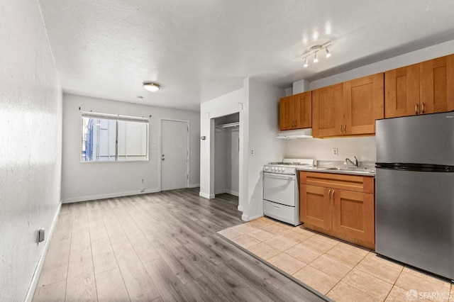 737 Minna St, San Francisco, CA 94103 - kitchen featuring a sink, light countertops, white gas range oven, freestanding refrigerator, and under cabinet range hood