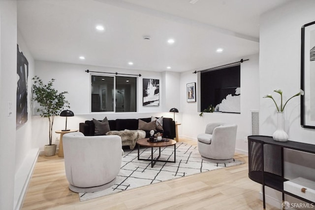 living area featuring wood finished floors, visible vents, baseboards, recessed lighting, and a barn door