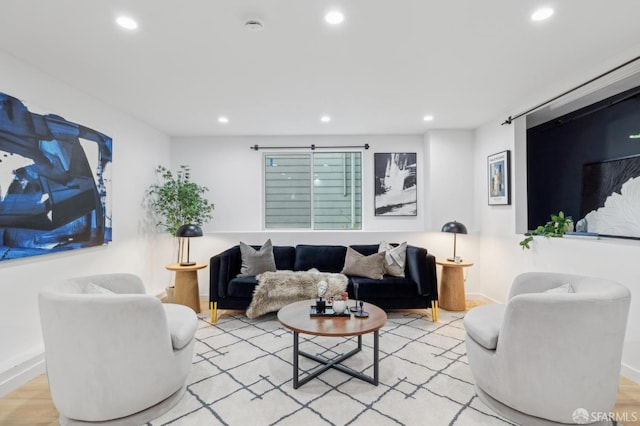 living area with a barn door, recessed lighting, baseboards, and wood finished floors