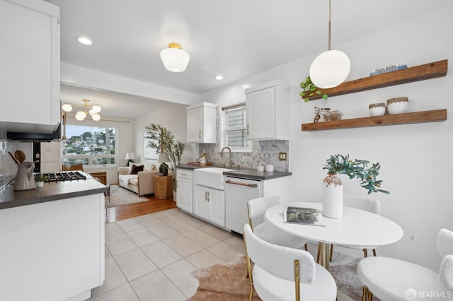 kitchen with white cabinetry, a sink, dishwasher, dark countertops, and tasteful backsplash