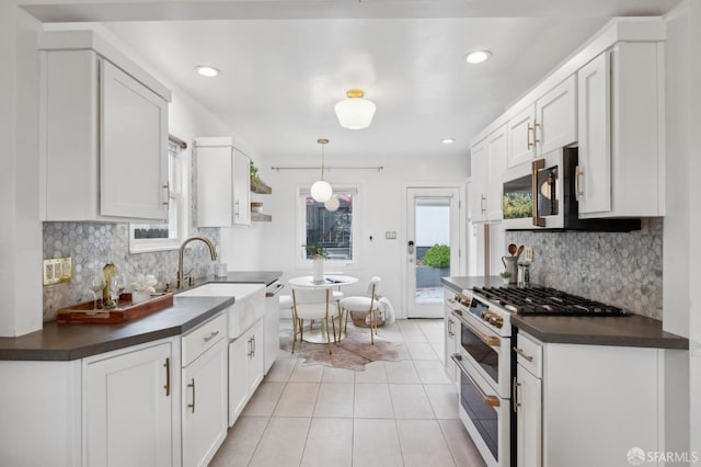 kitchen featuring light tile patterned floors, dark countertops, double oven range, a sink, and stainless steel microwave