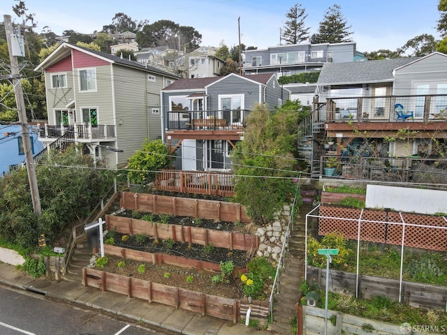 back of property featuring a garden, stairway, and a residential view