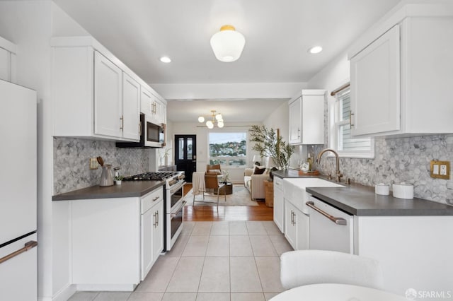 kitchen featuring dark countertops, white appliances, white cabinetry, and light tile patterned flooring