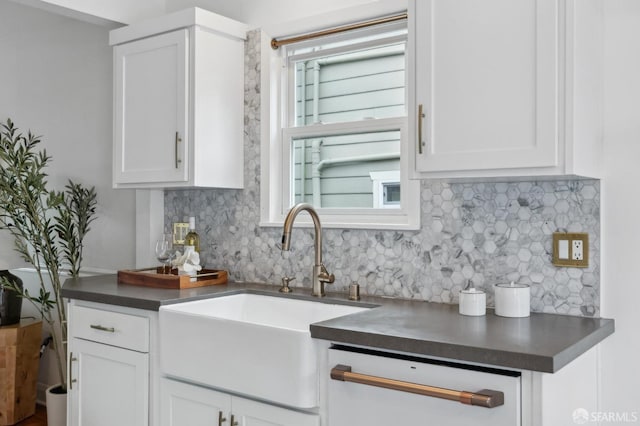 kitchen featuring dark countertops, plenty of natural light, white cabinetry, and a sink