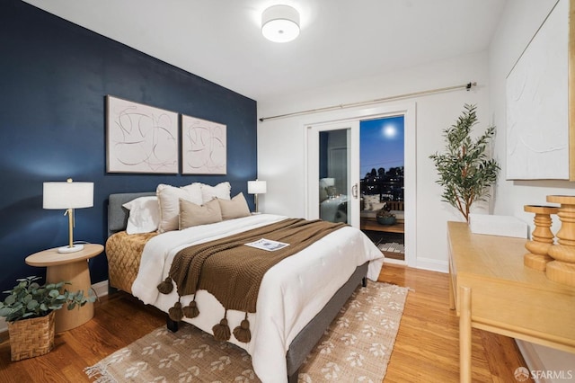 bedroom featuring baseboards, wood finished floors, and access to exterior