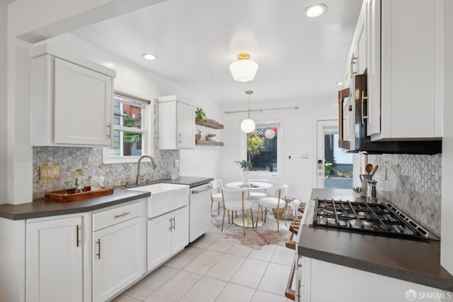 kitchen featuring a sink, stainless steel gas cooktop, dark countertops, dishwasher, and a healthy amount of sunlight