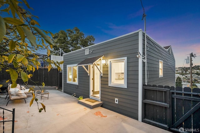 rear view of property featuring a patio area, an outdoor structure, and fence