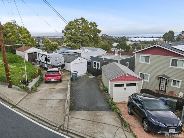 view of front of house with a detached garage and a water view