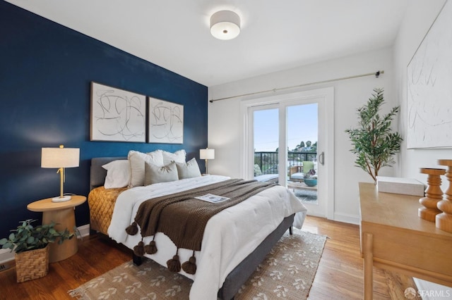 bedroom with access to exterior, wood finished floors, and baseboards