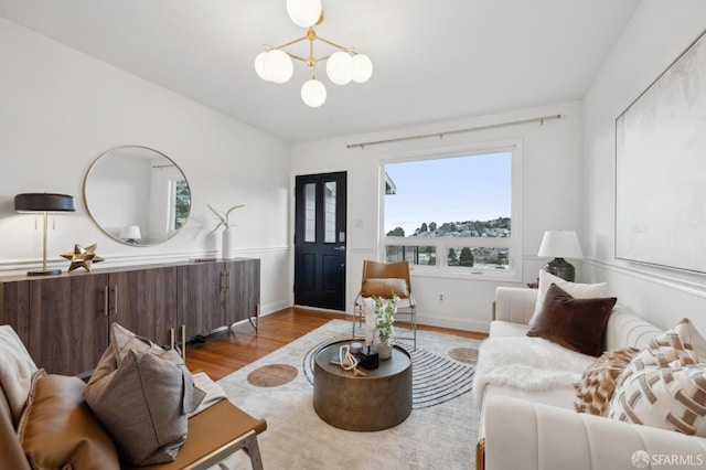 living area featuring baseboards, wood finished floors, and a chandelier