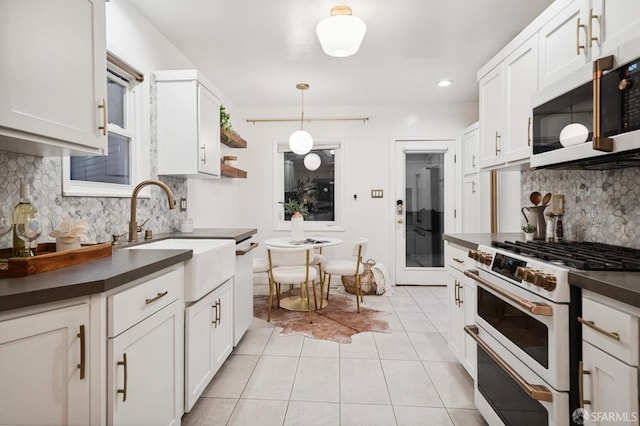 kitchen with white appliances, light tile patterned floors, a sink, white cabinetry, and dark countertops