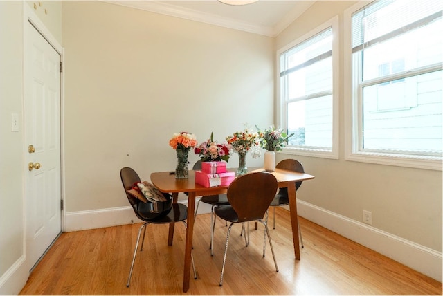 dining area with ornamental molding, light wood-style flooring, and baseboards