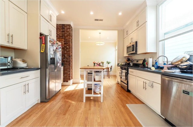 kitchen with visible vents, white cabinets, appliances with stainless steel finishes, dark countertops, and crown molding